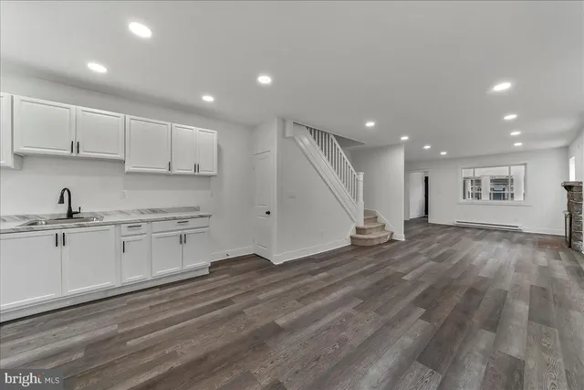 a open kitchen with kitchen island granite countertop a sink window and white cabinets