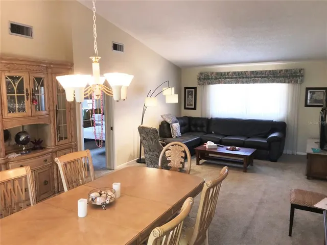 a living room with furniture a chandelier and a dining table