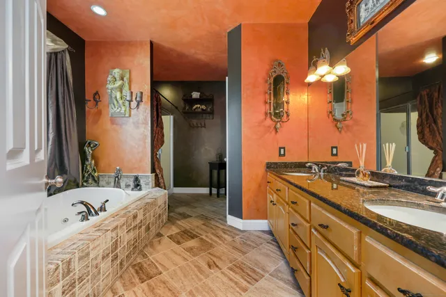 a bathroom with a granite countertop double vanity sink a mirror and a shower