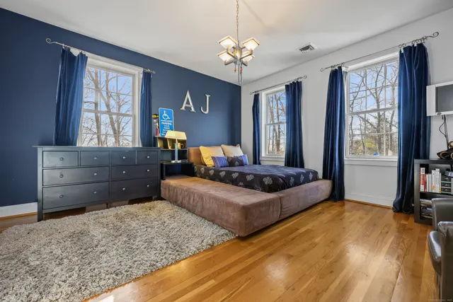 a living room with couches and dresser with wooden floor