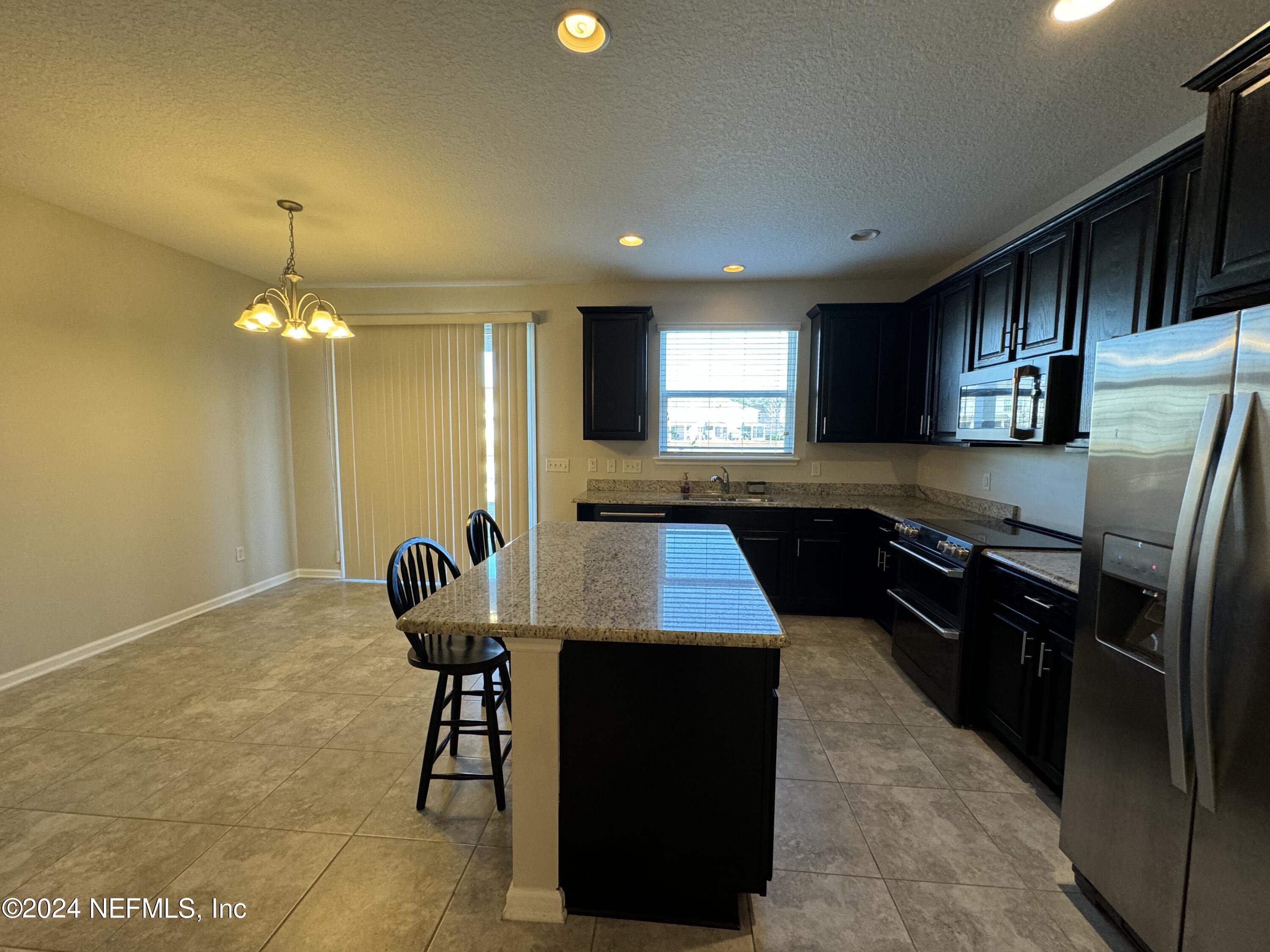 144 Nelson Lane St. Johns, FL 32259 - Photo 7 of 18 a kitchen with stainless steel appliances kitchen island granite countertop a stove a sink and a refrigerator