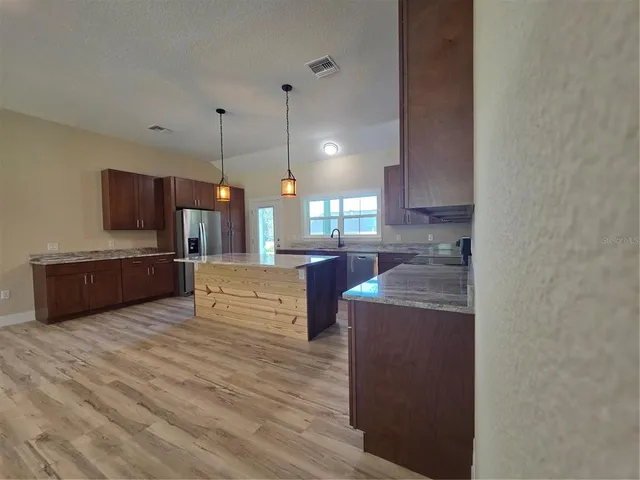 a large kitchen with a center island and stainless steel appliances