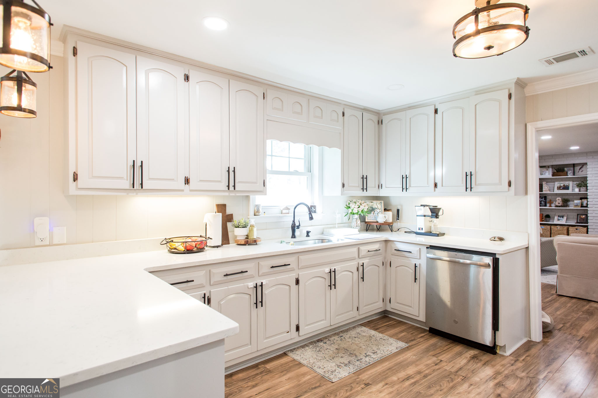 6737 Hacklebarney Road Blackshear, GA 31516 - Photo 9 of 40 a kitchen with a sink dishwasher a stove and white cabinets with wooden floor