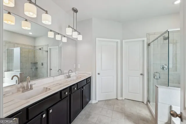 a bathroom with a double vanity sink a large mirror and shower