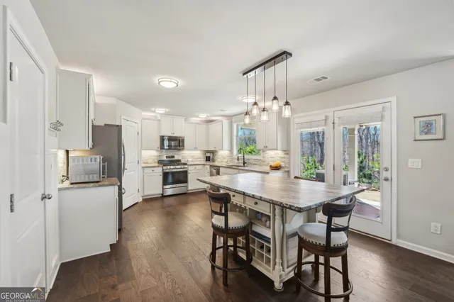 a kitchen with stainless steel appliances kitchen island granite countertop a table chairs and a refrigerator