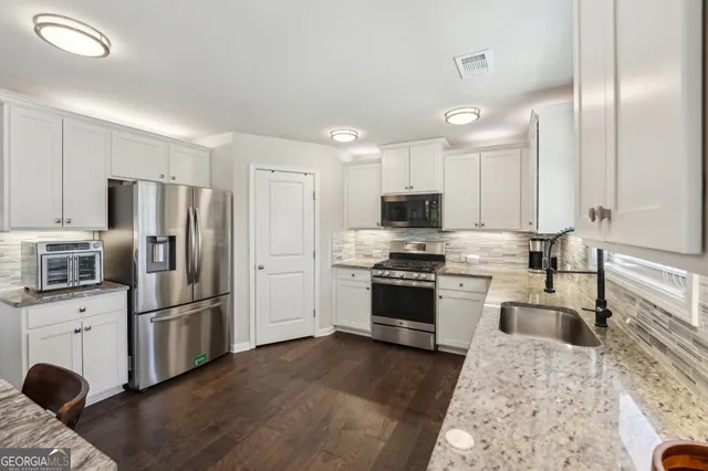 a kitchen with granite countertop a refrigerator stove and sink
