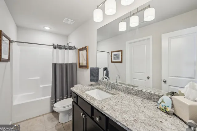a bathroom with a granite countertop sink a toilet and shower
