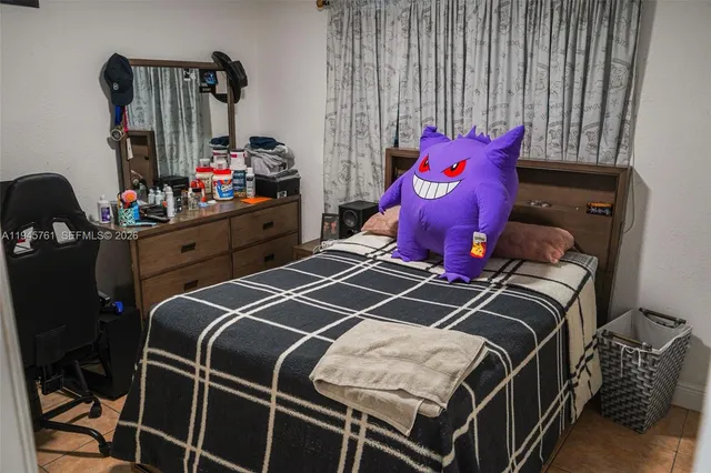 a bedroom with a bed a dresser and a large window