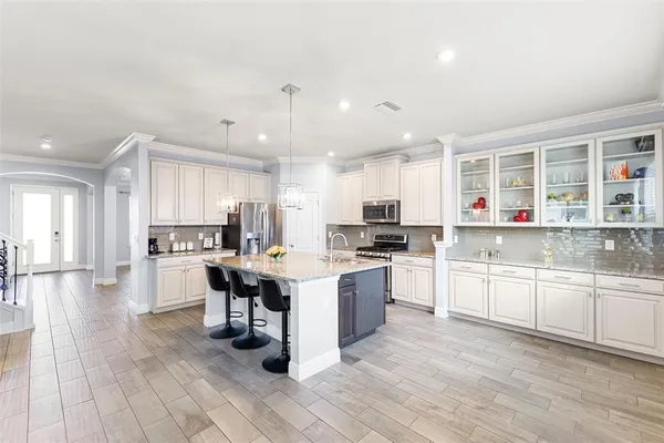 a kitchen with stainless steel appliances kitchen island granite countertop a stove top oven a sink a dining table and chairs