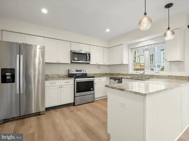 a kitchen with kitchen island granite countertop a stove a sink and a refrigerator