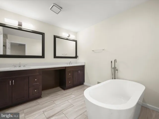 a bathroom with a tub sink and mirror