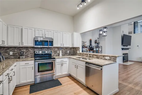 a kitchen with stainless steel appliances granite countertop a stove top oven a sink and white cabinets