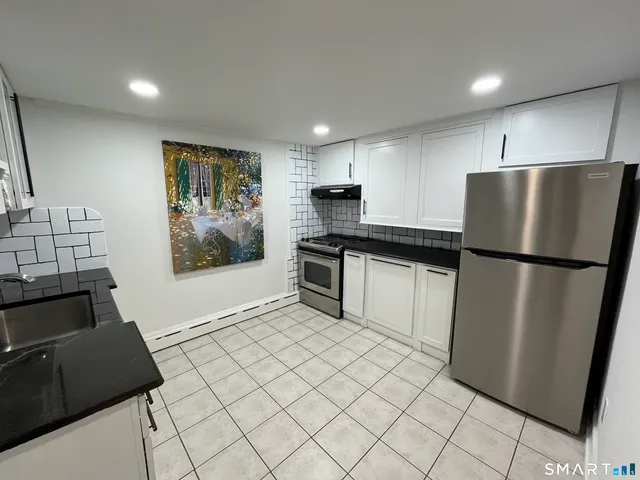 a kitchen with granite countertop a refrigerator and a stove top oven
