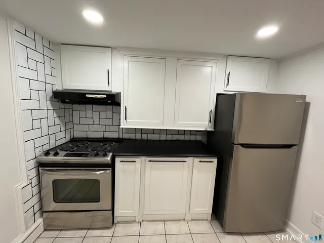 a kitchen with a refrigerator a stove and white cabinets