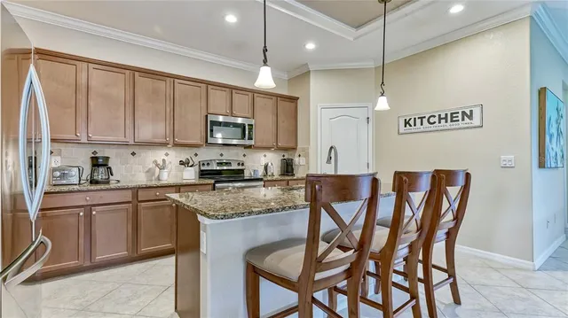 a kitchen with stainless steel appliances granite countertop a chairs a sink and a refrigerator