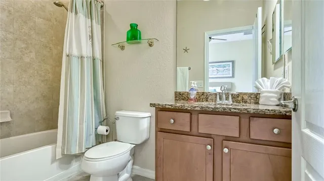 a bathroom with a granite countertop toilet sink and mirror