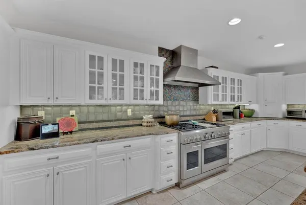 a large kitchen with kitchen island granite countertop a sink and white cabinets