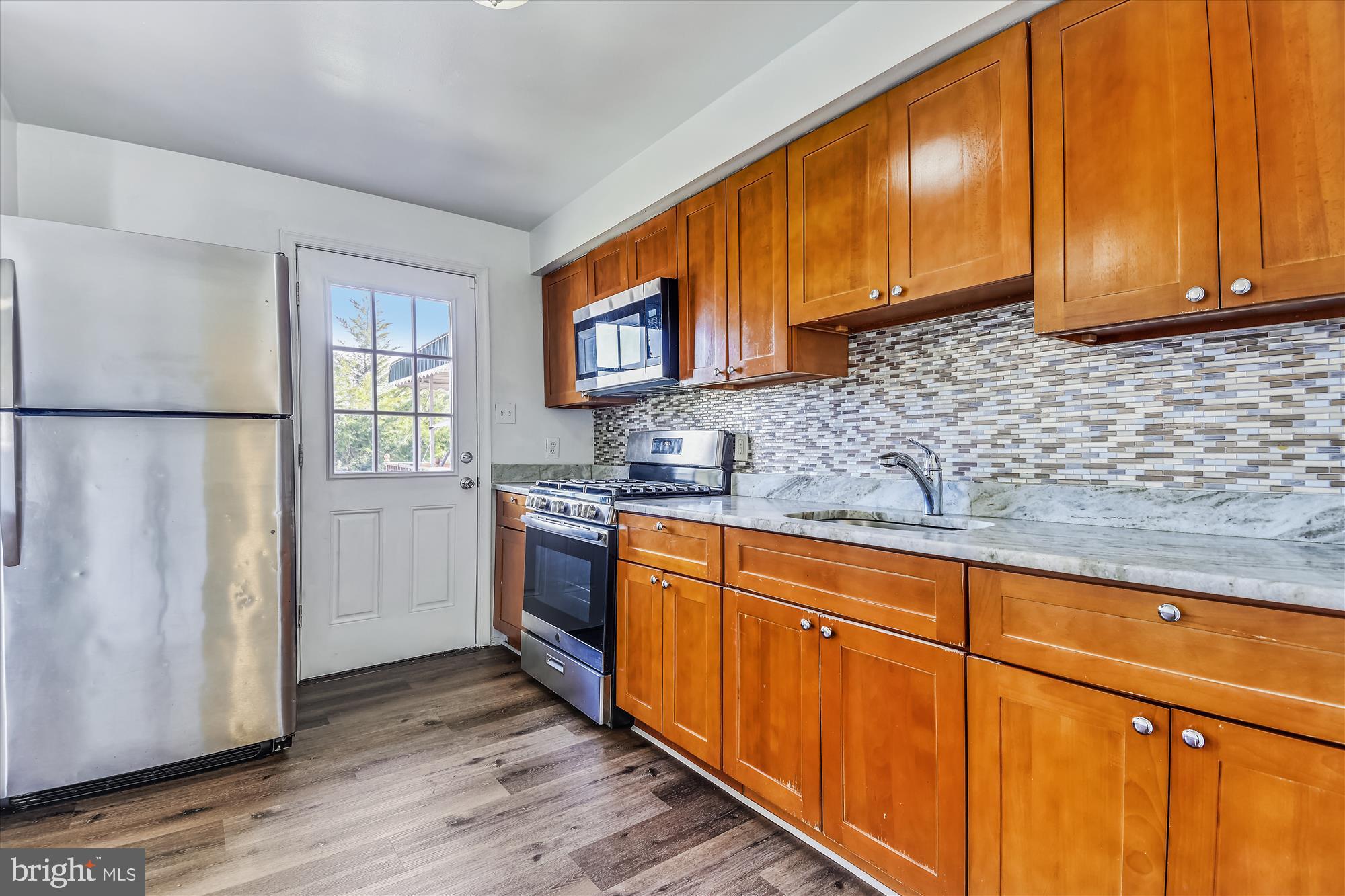 621 Kingston Road Middle River, MD 21220 - Photo 7 of 26 a kitchen with stainless steel appliances granite countertop a refrigerator a sink dishwasher and wooden cabinets with wooden floor