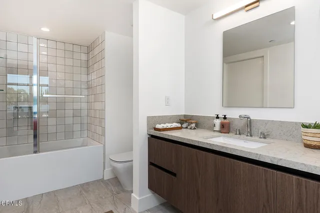 a bathroom with a granite countertop sink a toilet and shower