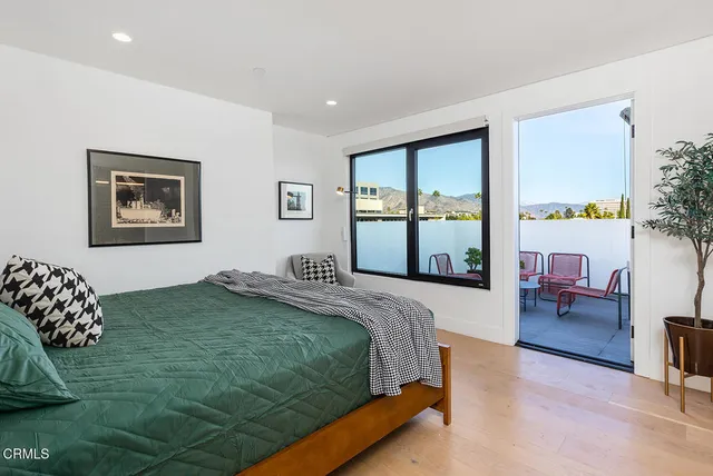 a bedroom with a bed painting on wall and a potted plant