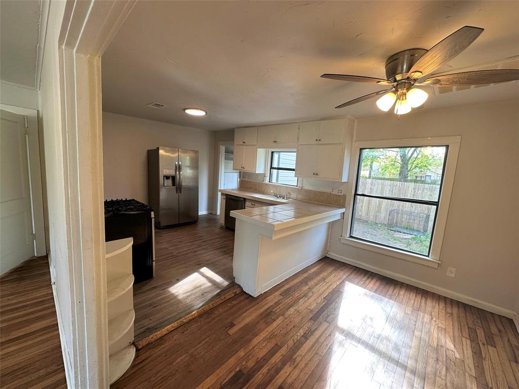 919 South Clements Street Gainesville, TX 76240 - Photo 4 of 11 a kitchen with stainless steel appliances granite countertop a refrigerator a sink dishwasher a stove and white countertops with wooden floor