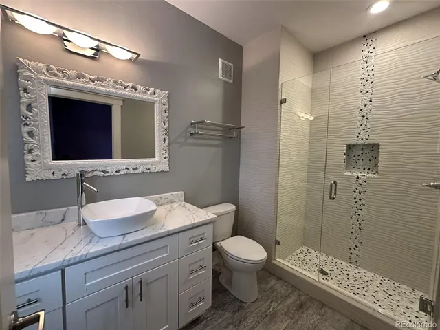 a bathroom with a granite countertop sink a toilet and shower