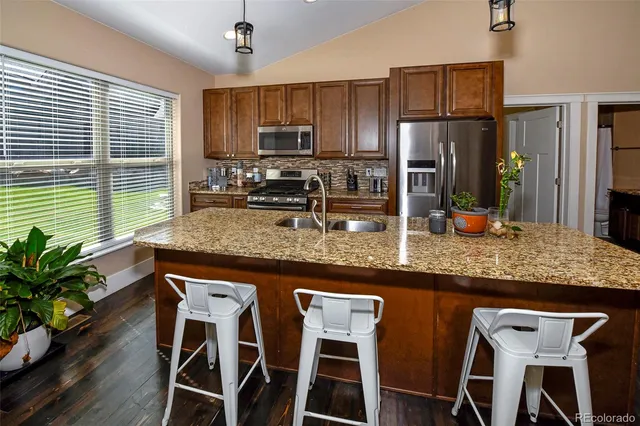 a kitchen with stainless steel appliances granite countertop a stove top oven a refrigerator and wooden floor