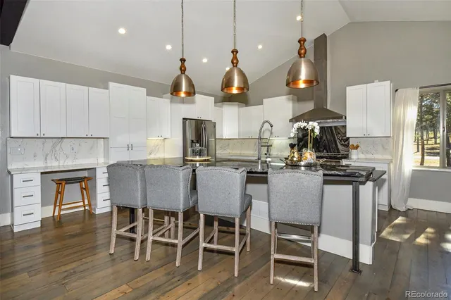 a kitchen with stainless steel appliances a dining table chairs and sink