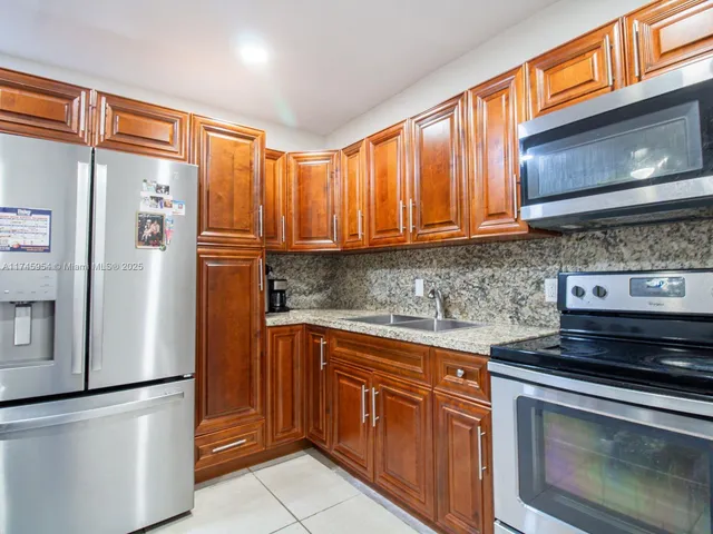 a kitchen with stainless steel appliances granite countertop a refrigerator stove and cabinets