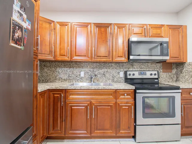 a kitchen with granite countertop wood cabinets and stainless steel appliances