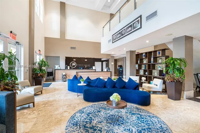 a living room with furniture potted plant and kitchen view