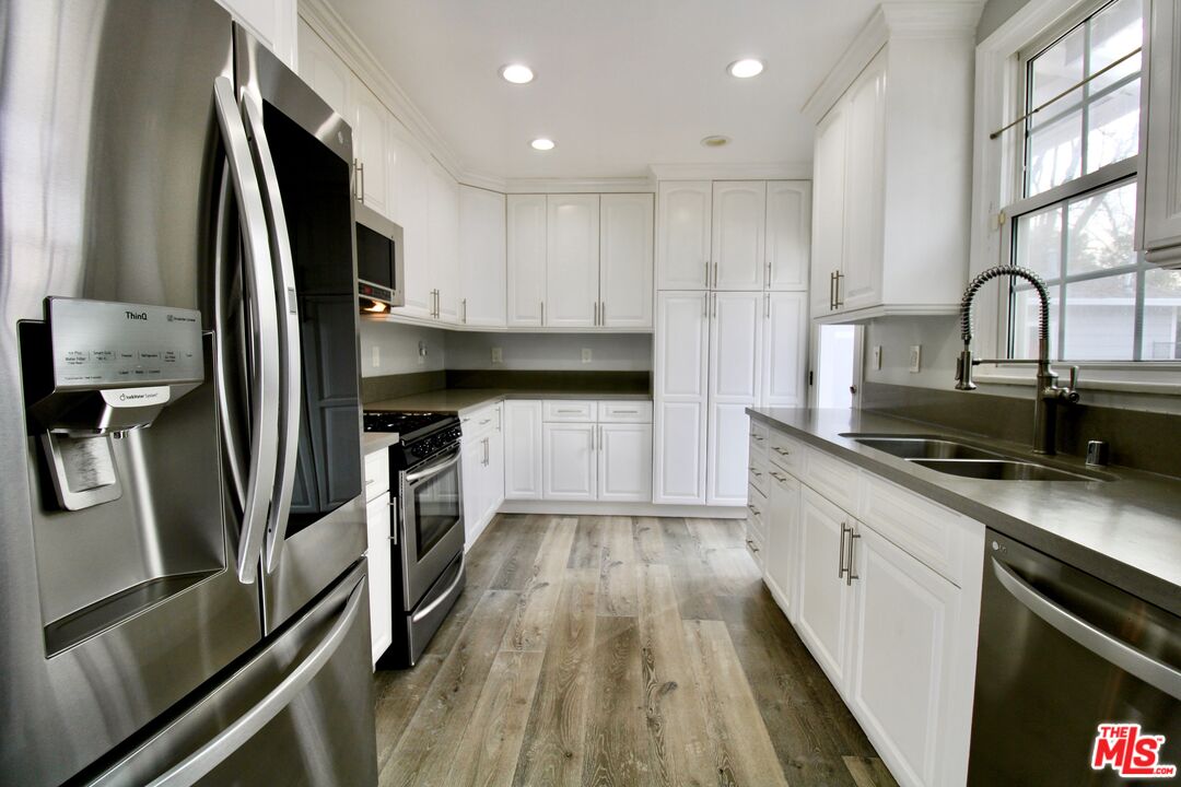 8421 Darby Avenue Northridge, CA 91325 - Photo 8 of 38 a kitchen with stainless steel appliances a refrigerator sink and wooden cabinets