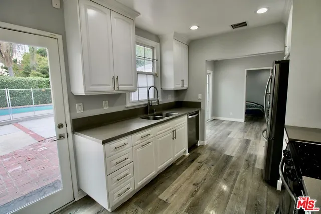 a kitchen with white cabinets and sink