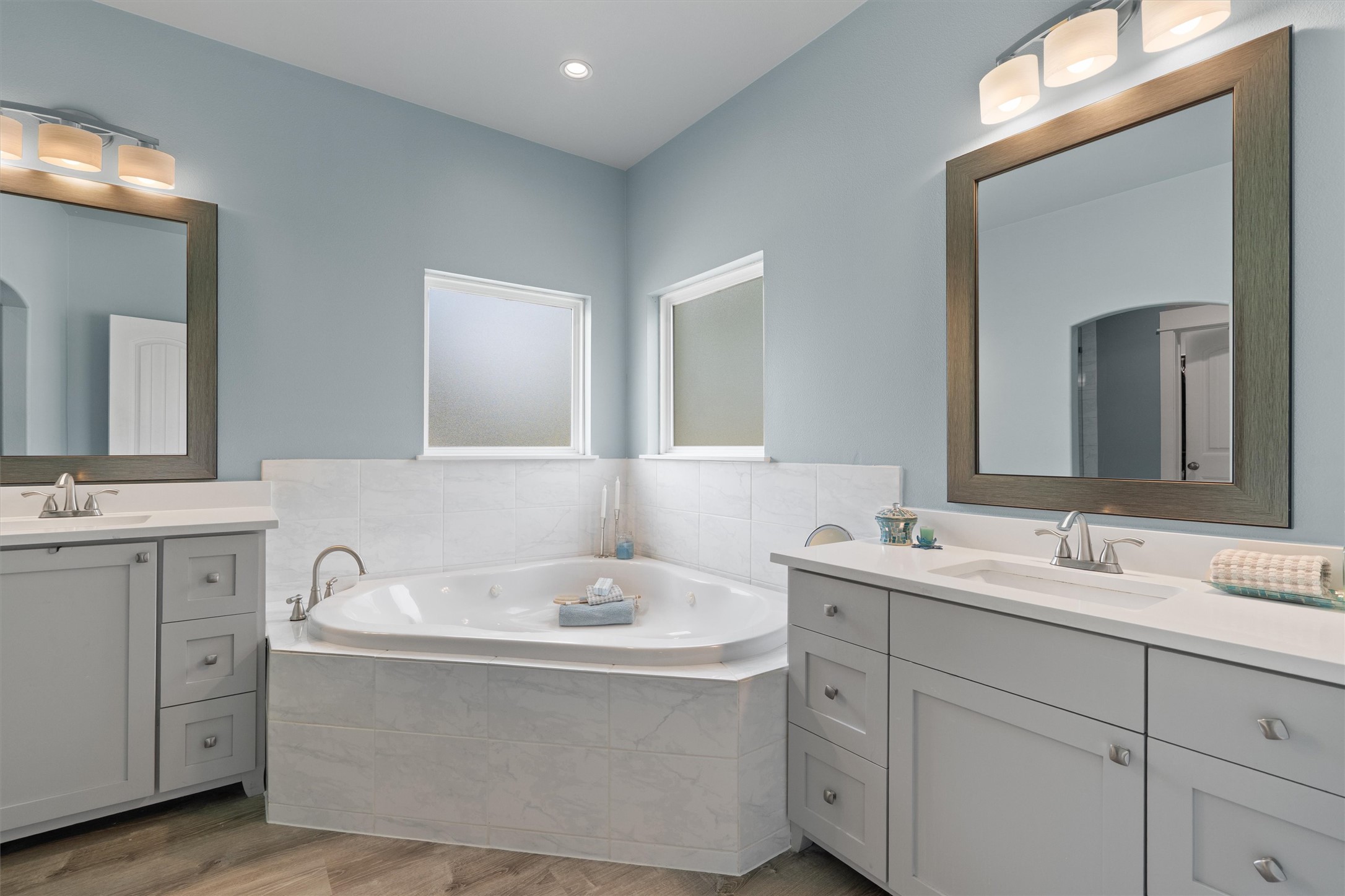 13105 Rooster Springs Road Austin, TX 78737 - Photo 12 of 38 Bathroom featuring a corner soaking tub, two separate vanities with white countertops, and light blue walls