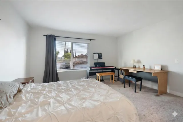 a bedroom with a bed table chair and a two windows