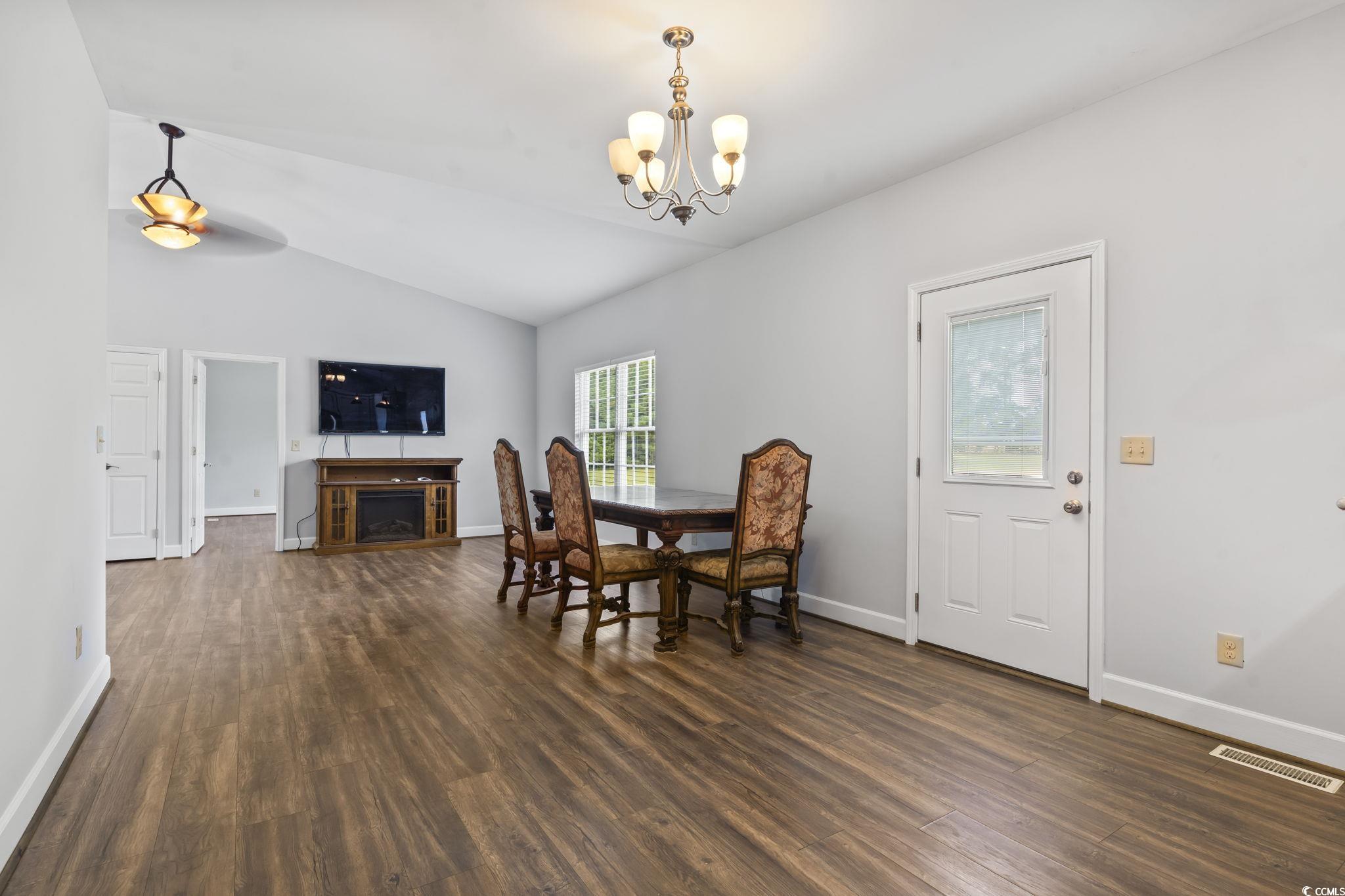 1585 Daisy Road Loris, SC 29569 - Photo 15 of 48 Dining area with vaulted ceiling, dark wood-style flooring, a fireplace, and a chandelier