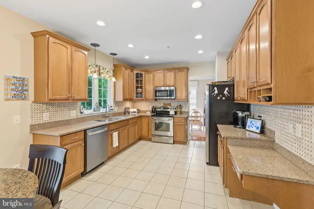 a kitchen with stainless steel appliances granite countertop a refrigerator a sink dishwasher a stove with white cabinets and wooden floor