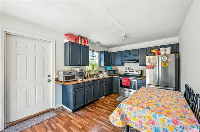 a kitchen with stainless steel appliances granite countertop a refrigerator and a wooden floor