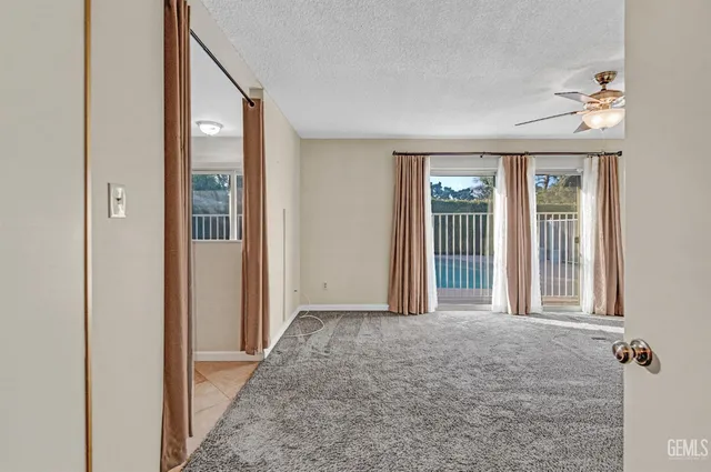 a view of a livingroom with a ceiling fan & windows