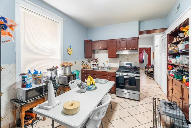 a kitchen with a refrigerator a stove a dining table and chairs