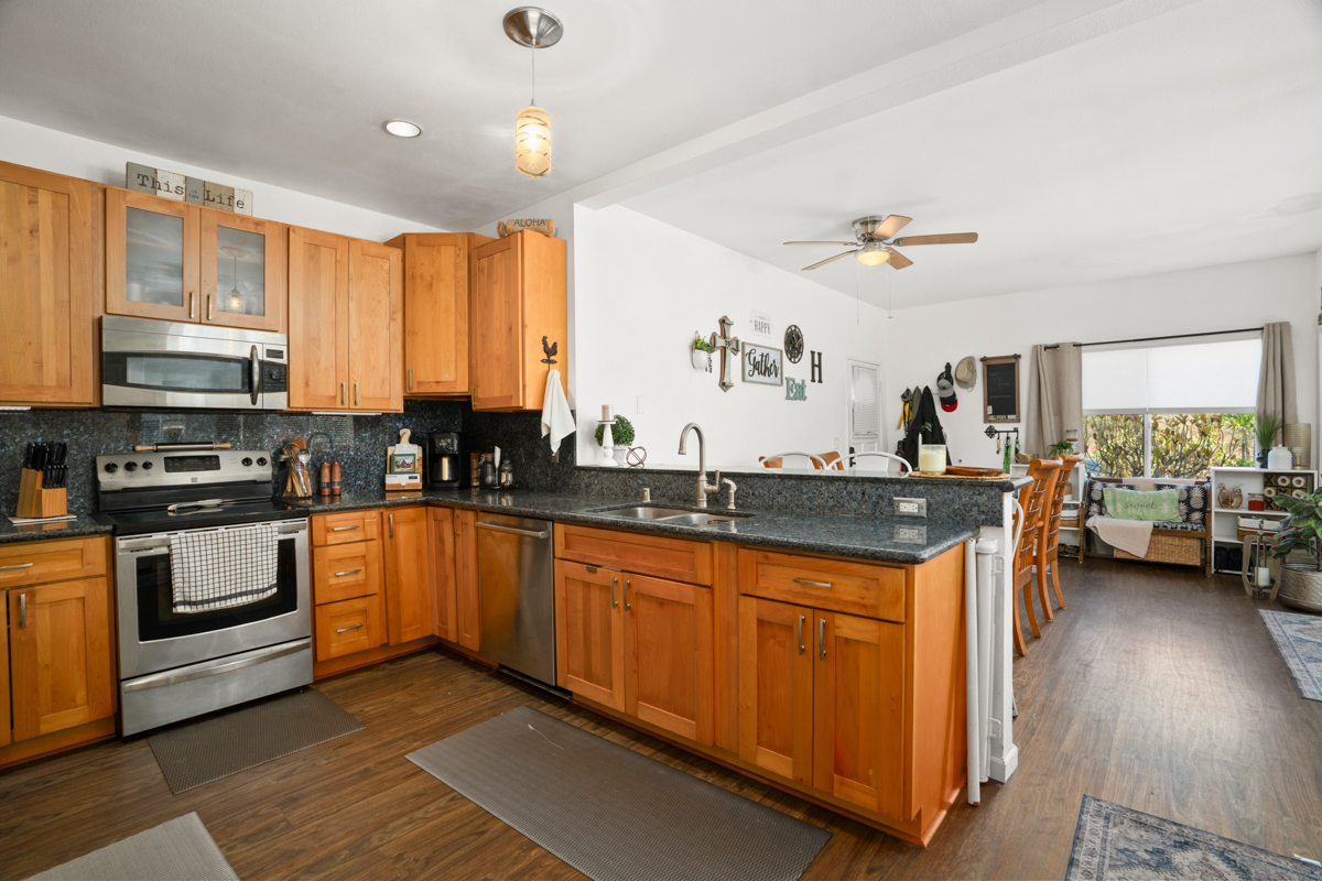 1831 Poipu Road, Unit 113 Koloa, HI 96756 - Photo 5 of 22 a kitchen with stainless steel appliances granite countertop a stove a sink and a microwave