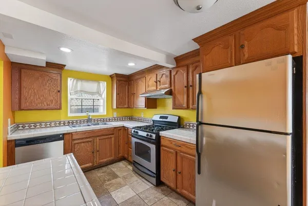 a kitchen with stainless steel appliances granite countertop a refrigerator a sink and a stove