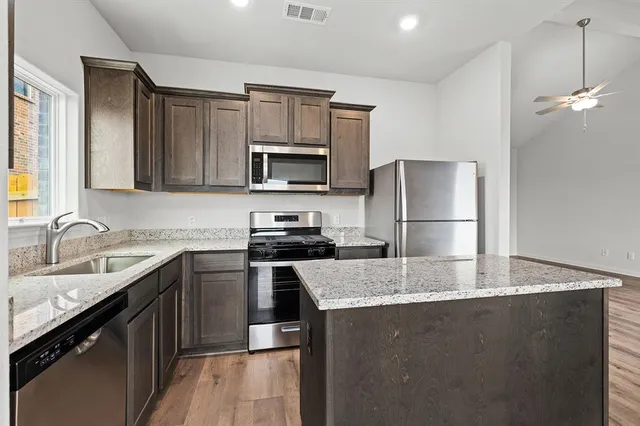 a kitchen with kitchen island granite countertop a sink dishwasher stove and refrigerator