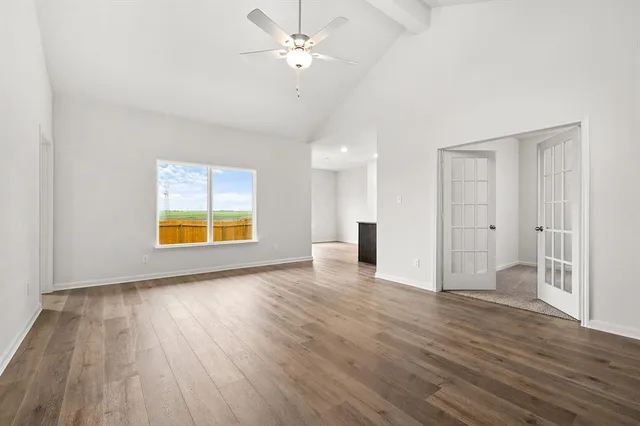 a view of an empty room with a window and wooden floor