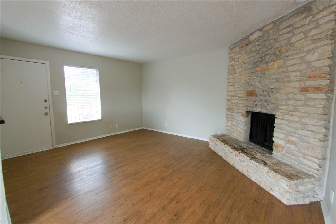 an empty room with a fireplace and wooden floor