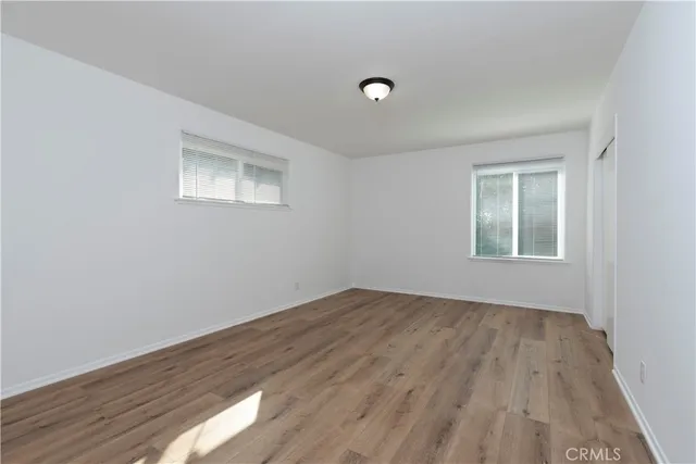 a view of an empty room with wooden floor and a window