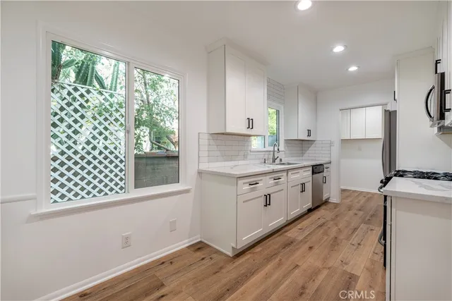 a kitchen with granite countertop a sink cabinets stainless steel appliances and a window