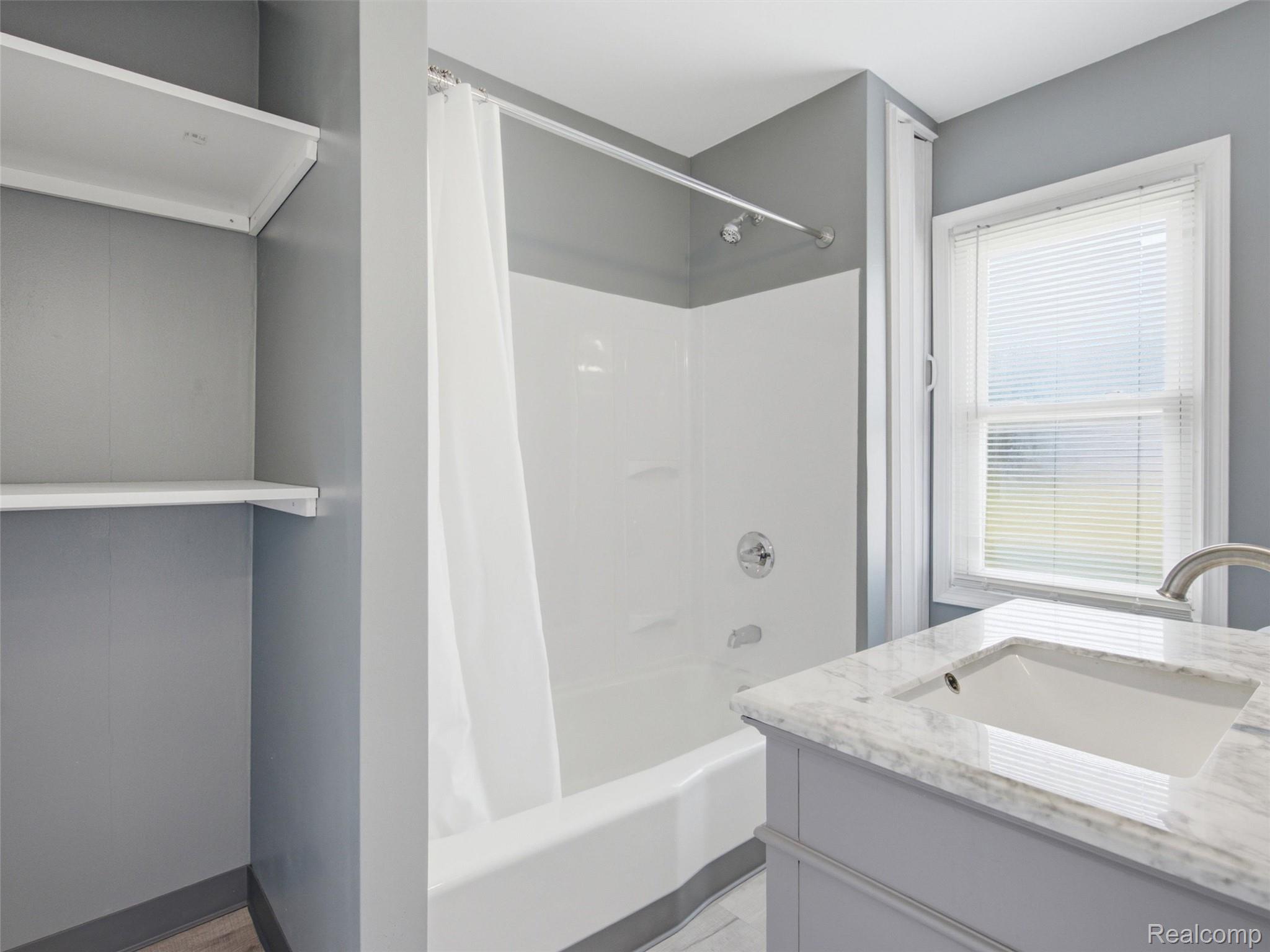 808 Corwin Court Pontiac, MI 48340 - Photo 22 of 34 Bathroom featuring a brand new white tub/shower combination with chrome fixtures, a single grey vanity with an integrated sink and light-colored countertop, and a built-in shelving unit