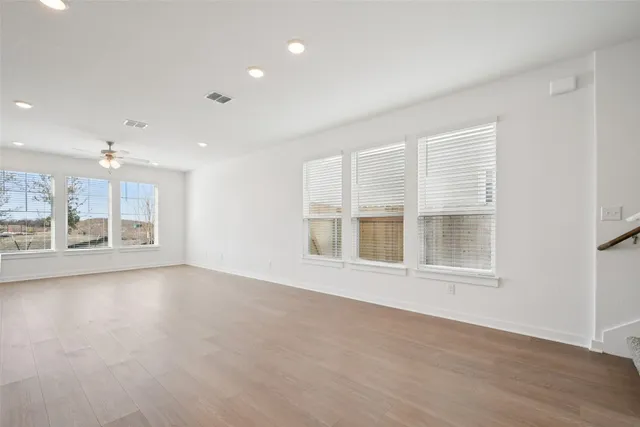 a view of an empty room with a window and wooden floor