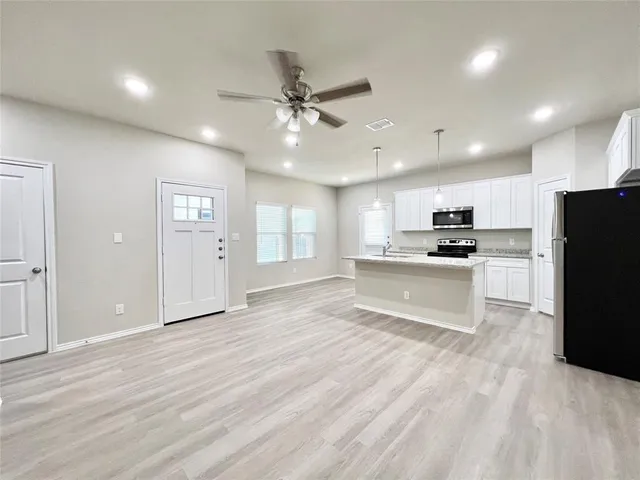a kitchen with stainless steel appliances kitchen island granite countertop a stove a sink and a refrigerator